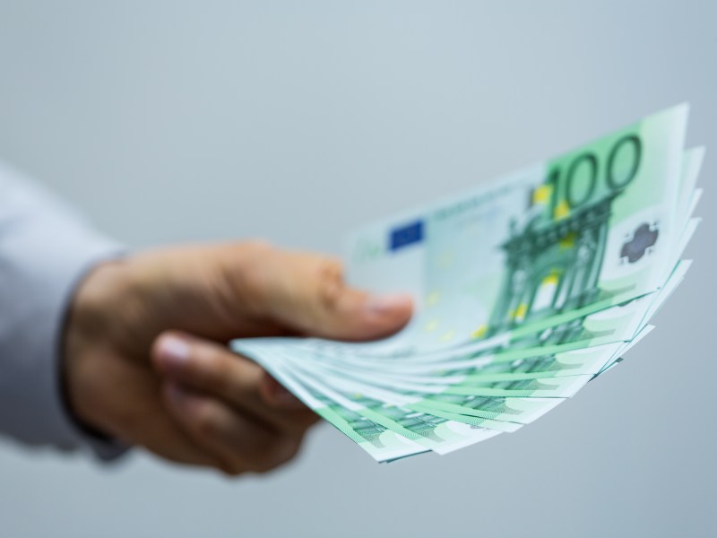 Ein Mann hält mehrere 100-Euro-Scheine in der Hand.