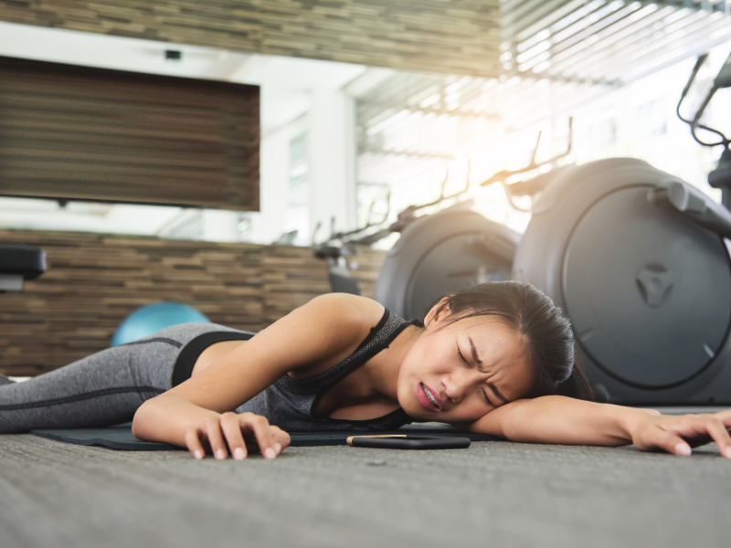 Frau liegt auf dem Boden im Fitnessstudio