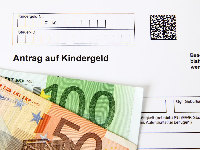 Auf einem Kindergeld-Antrag liegen zwei Geldscheine.