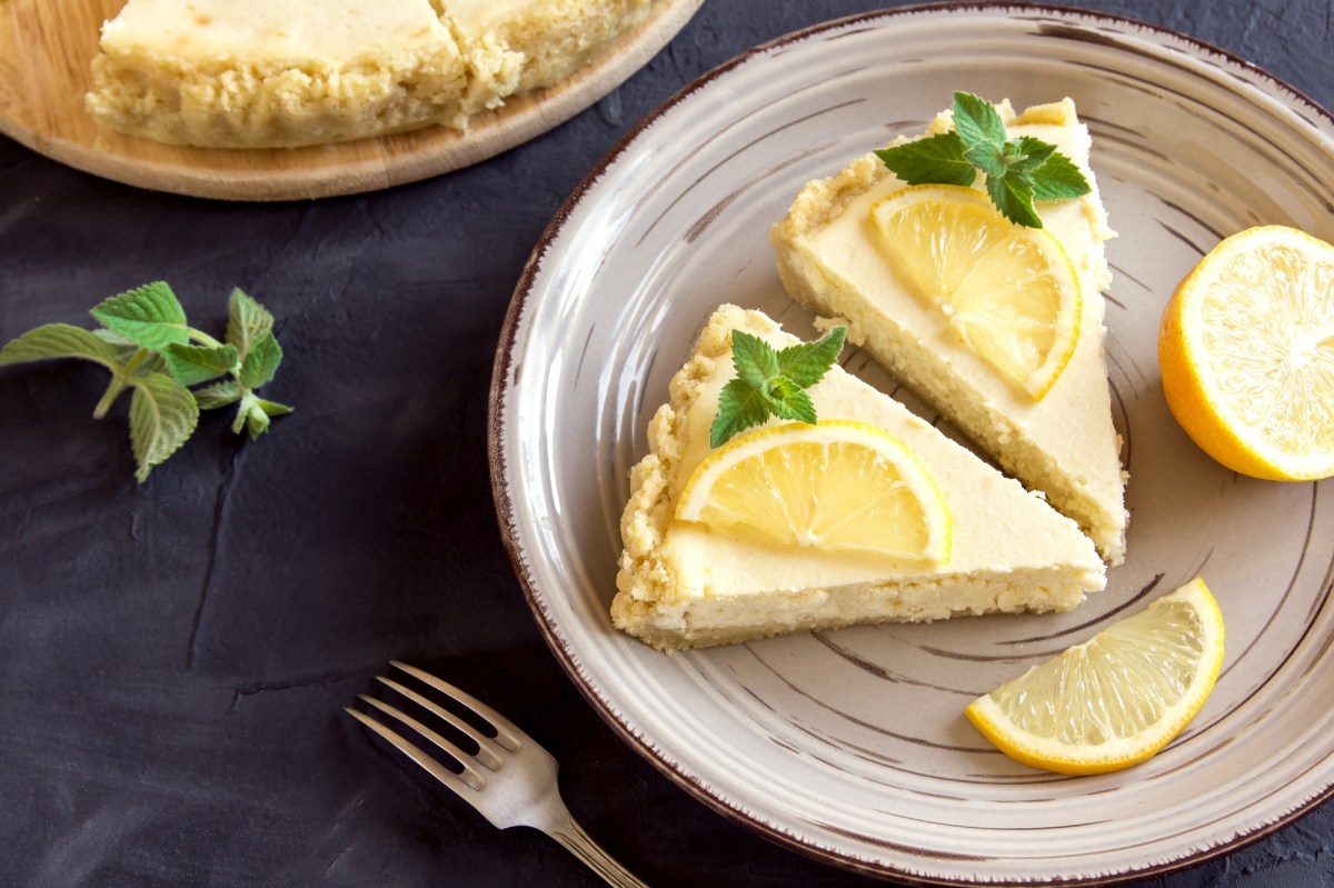 Teller mit zwei Stücken Zitronen-Cheesecake auf dunklem Untergrund