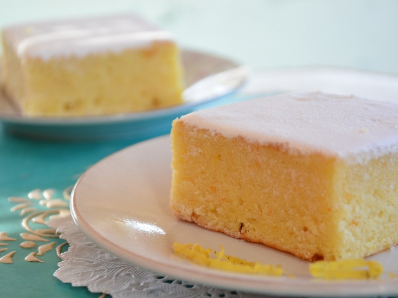 zwei Stück Buttermilchkuchen mit Zitrone auf je einem Teller, garniert mit Zuckerguss.