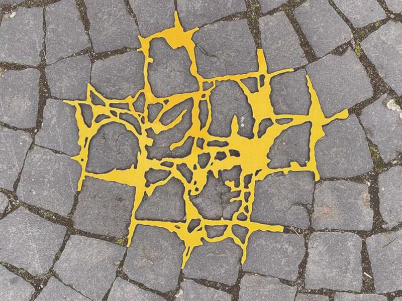 Gelber Kunststoff füllt Risse auf Kopfsteinpflaster, Kintsugi Art