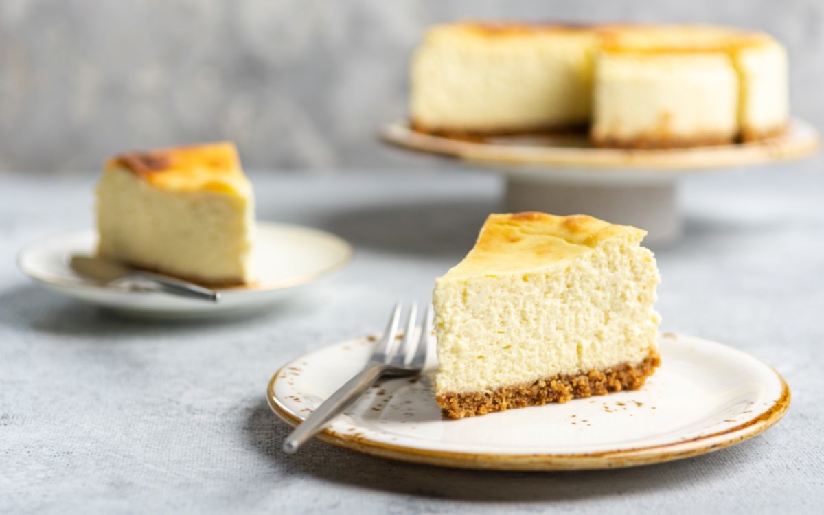 Zwei Stücke Käsekuchen mit Mascarpone auf zwei Tellern. Im Hintergrund ist der restliche Kuchen zu sehen.