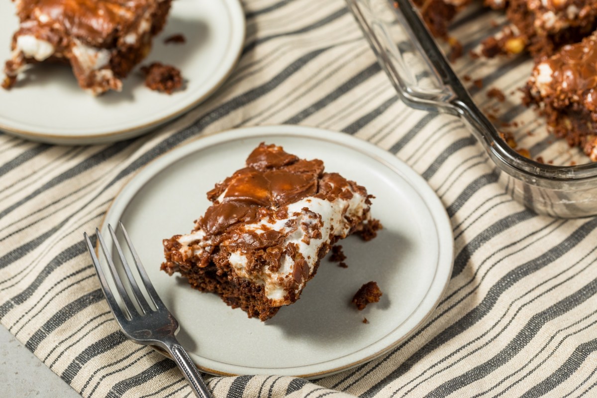 Ein Stück Mississippi Mud Cake auf einem weißen Teller. Daneben steht der Rest des Kuchens.