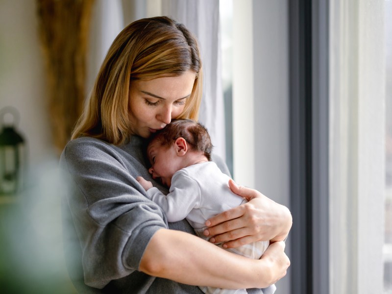 Eine Mutter umarmt ihr kleines Baby zu Hause.