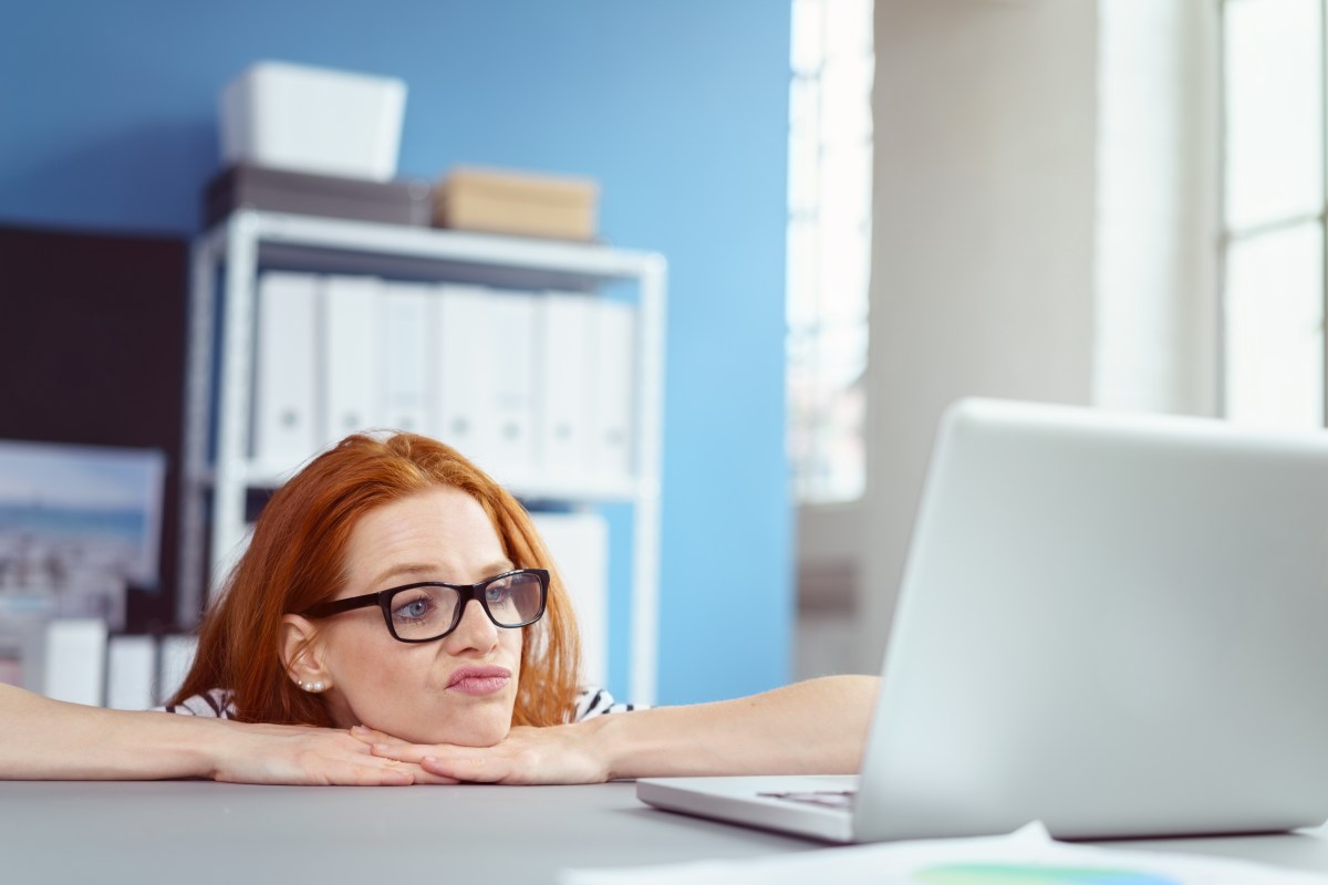 Frau mit Brille schaut genervt auf ihren Laptop.