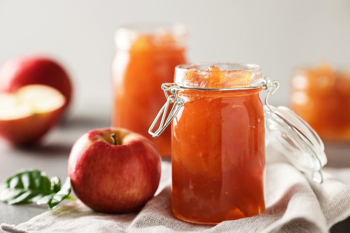 Drei Gläser Apfelgelee und frische Äpfel