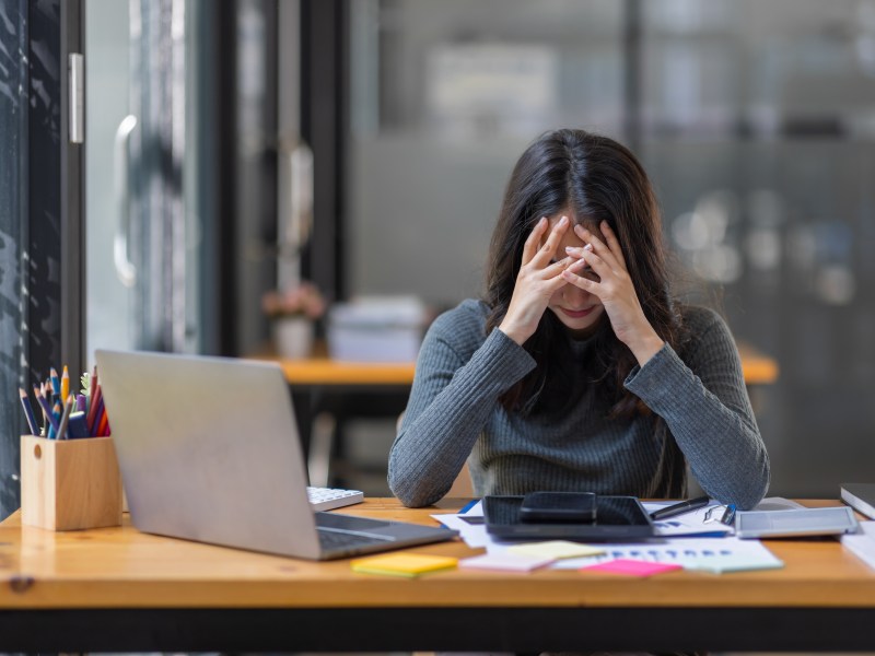 Eine Frau schlägt ihre Hände vor den Kopf. Sie sitzt im Büro.