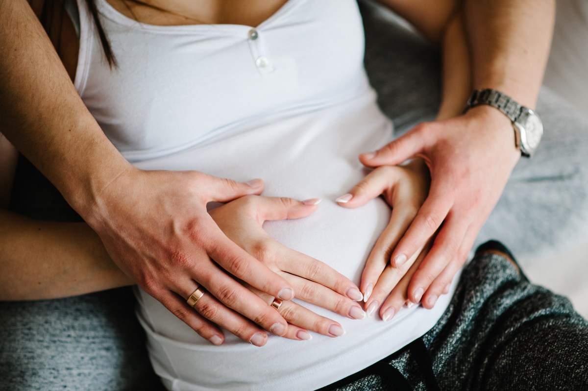 Ausgeschnittenes Bild eines Mannes, der den Bauch seiner schwangeren Frau hält.