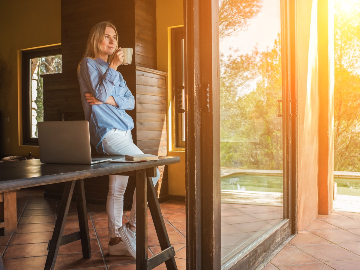 Frau mit Laptop und Tee trinkend, verbringt ihre Freizeit auf der Terrasse.