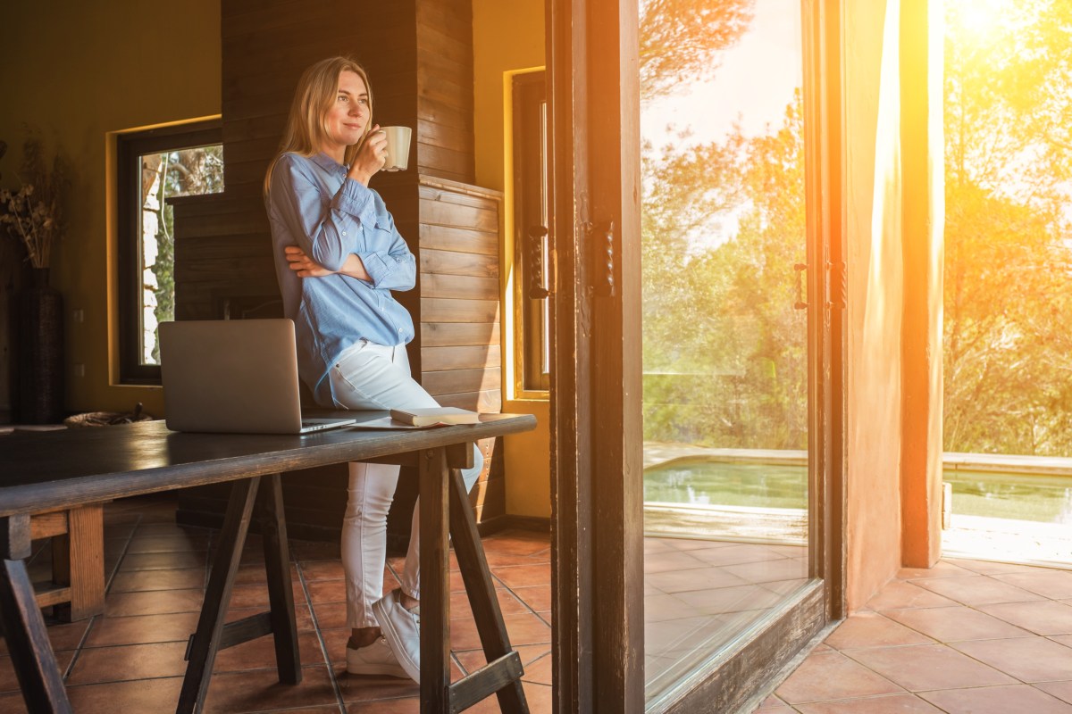 Frau mit Laptop und Tee trinkend, verbringt ihre Freizeit auf der Terrasse.