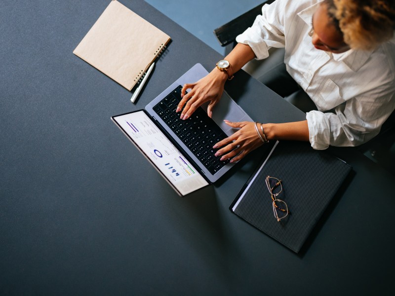 Eine Frau sitzt am Laptop und arbeitet.