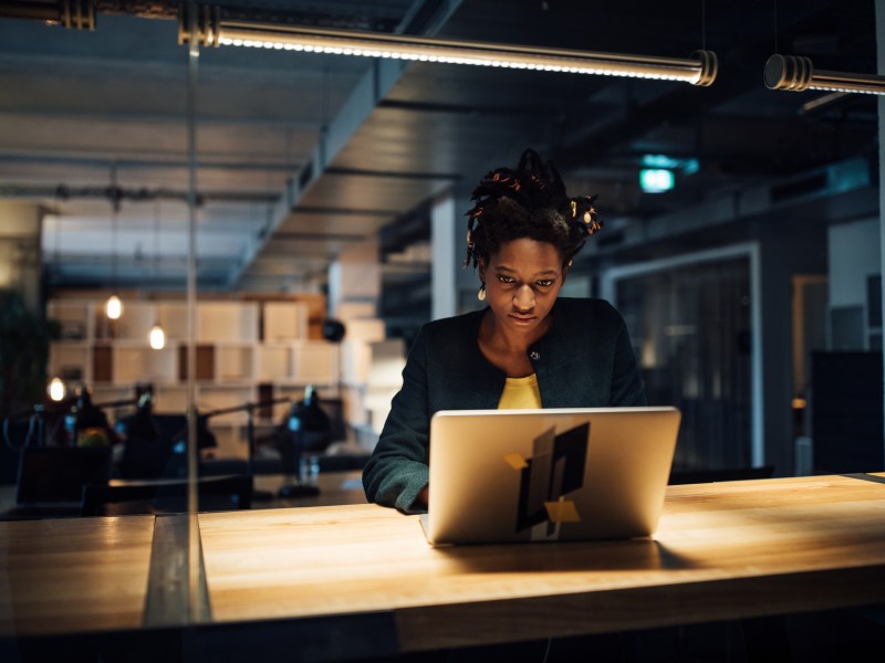 Geschäftsfrau arbeitet spät am Laptop, während sie im Büro am Schreibtisch sitzt