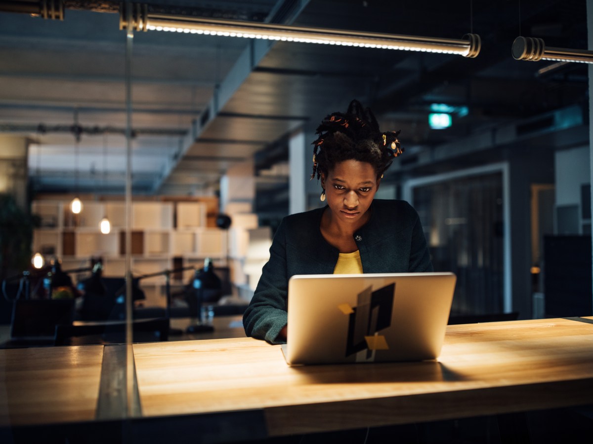 Geschäftsfrau arbeitet spät am Laptop, während sie im Büro am Schreibtisch sitzt