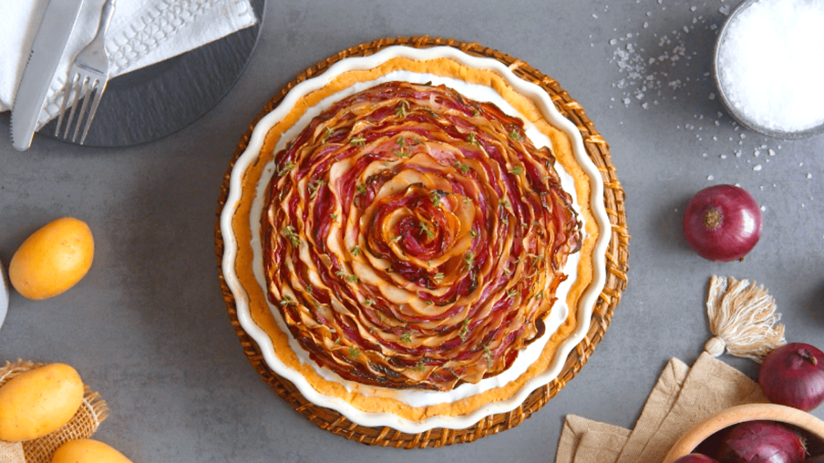 Zwiebelkuchen mit Mürbeteig, serviert in einer Tarteform.