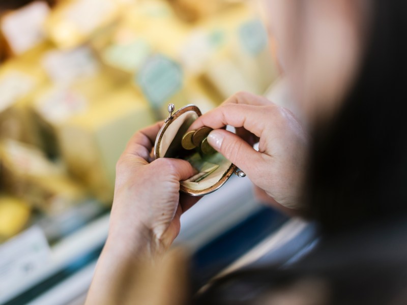 Nahaufnahme einer Frau, die am Marktstand bezahlt. Sie hält eine Geldbörse in der Hand.