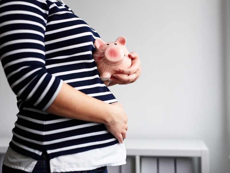 Kindergeld: Schwangere Frau mit Sparschwein in der Hand.