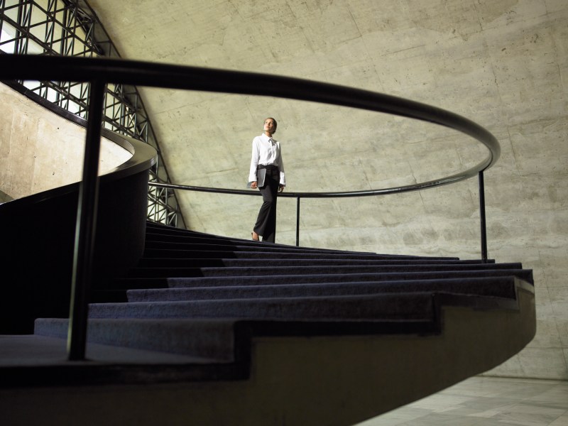 Eine Frau im Business-Outfit steht auf einer Treppe.