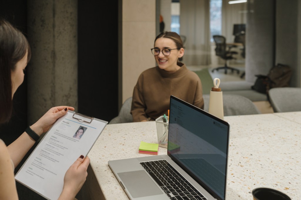 Eine junge Frau mit Brille sitzt in einem Vorstellungsgespr&auml;ch.