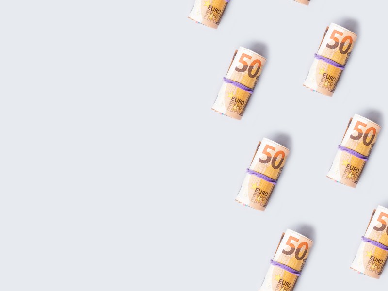 50-Euro-Banknotenrollen auf grauem Hintergrund.