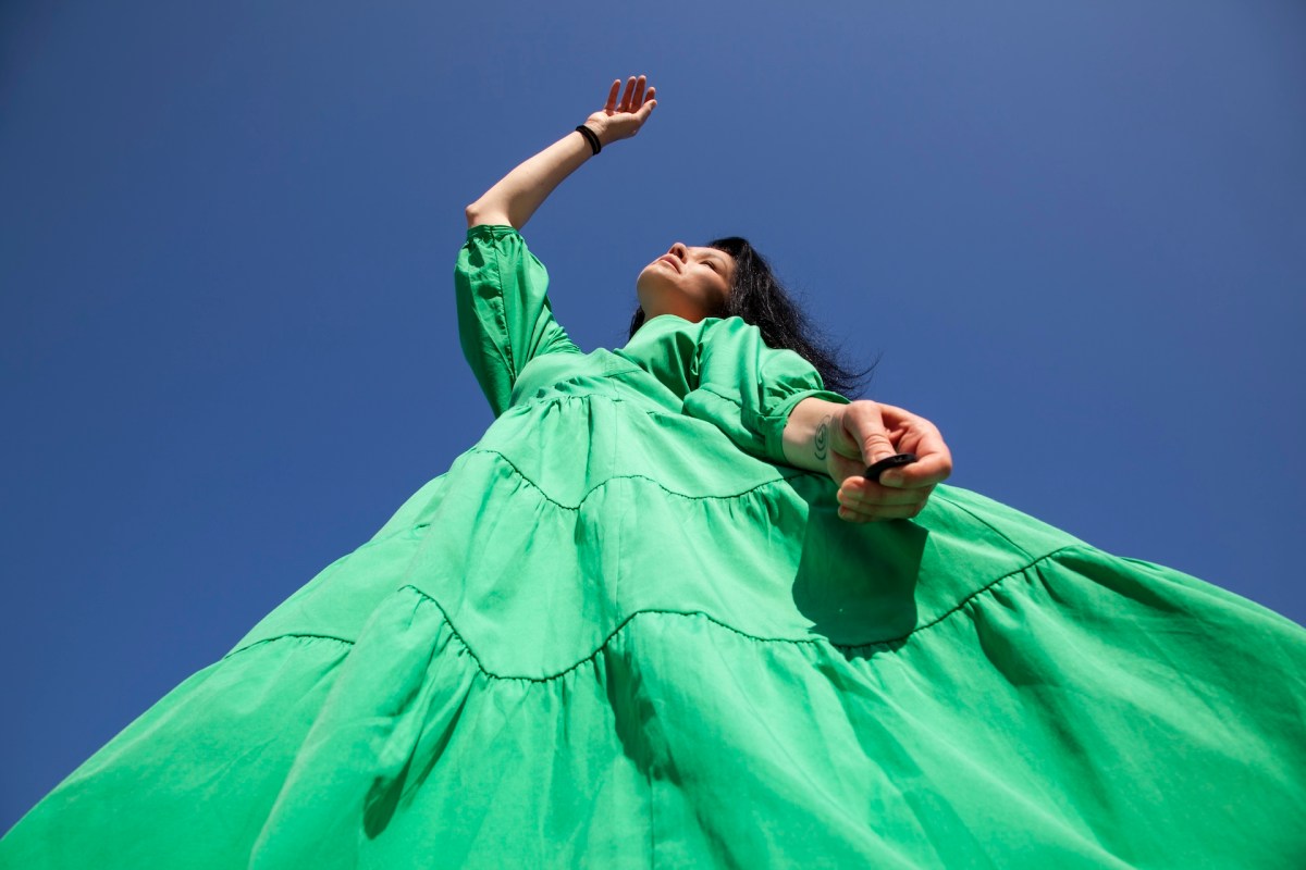 Eine Frau mit schwarzen Haaren in einem grünen Kleid.
