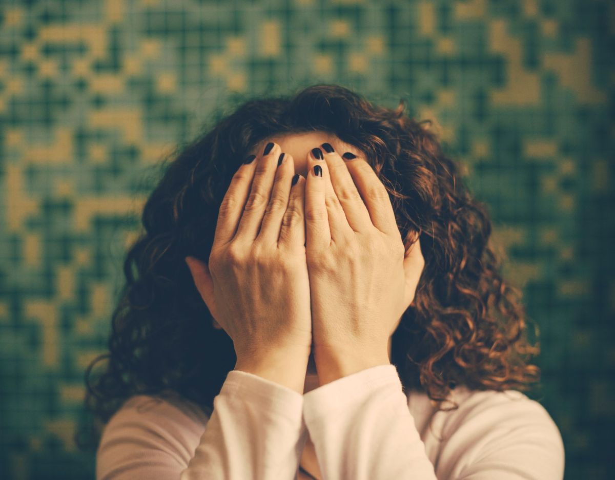 Frau versteckt Gesicht in den Händen