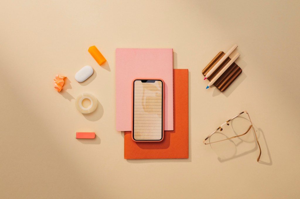 Büromaterialien: ein minimalistisches Stillleben auf einem Tisch mit einem Smartphone.