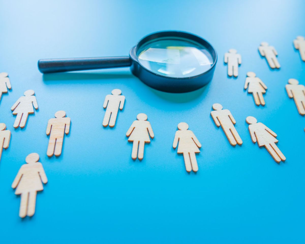 Eine Lupe und Frauen aus Papier.